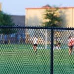 football field and players behind chain link fence